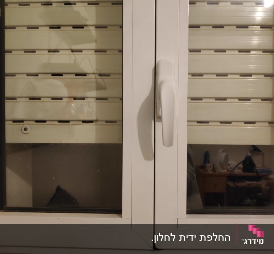 חלון עם תריסים סגורים וידית לבנה